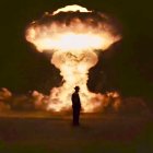 Silhouetted person against glowing mushroom cloud in desert landscape