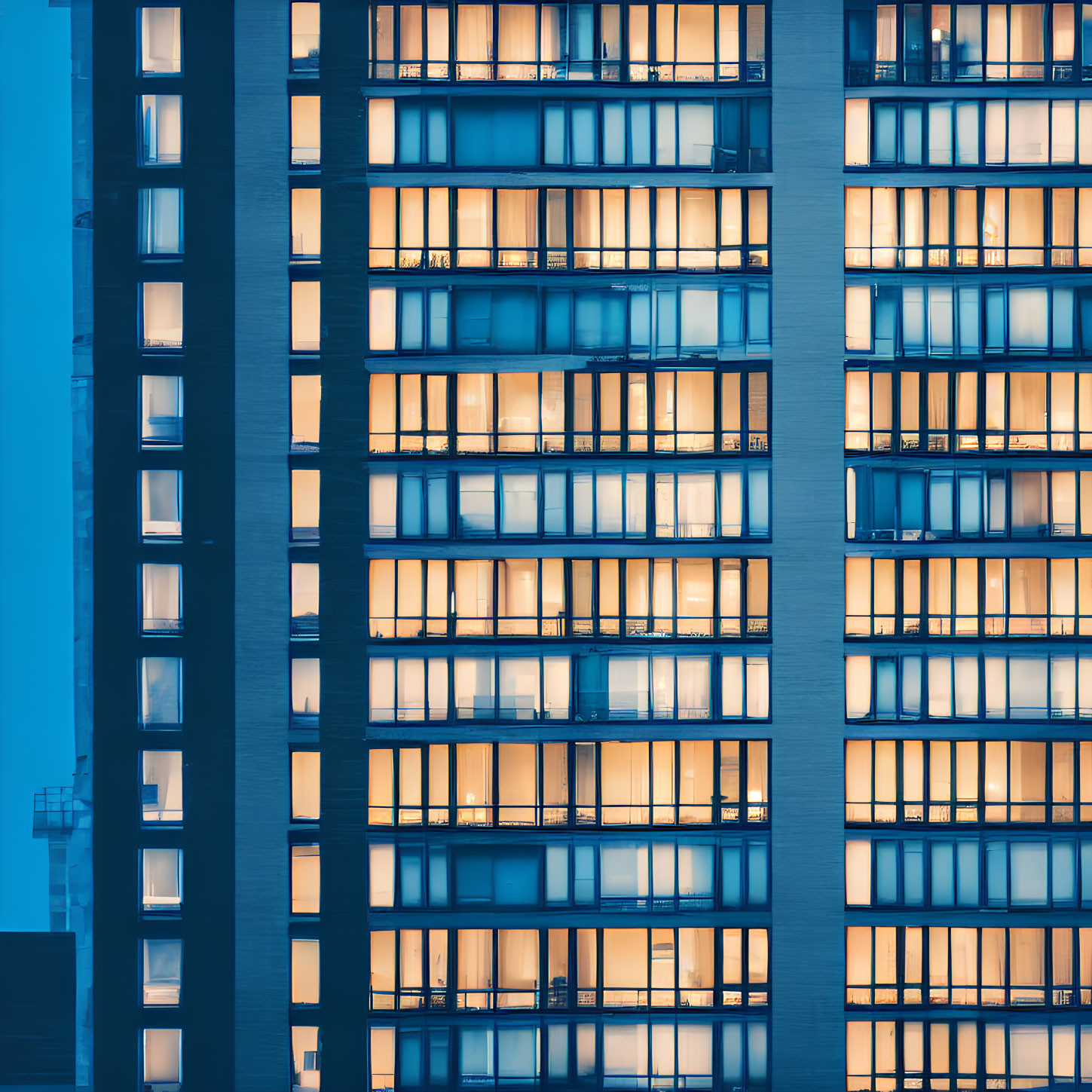 High-rise building facade with illuminated windows at dusk