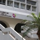 Modern building with white arches and staircases in lush green palm tree setting