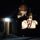 Dimly Lit Church at Night with Glowing Cross and Stained-Glass Windows