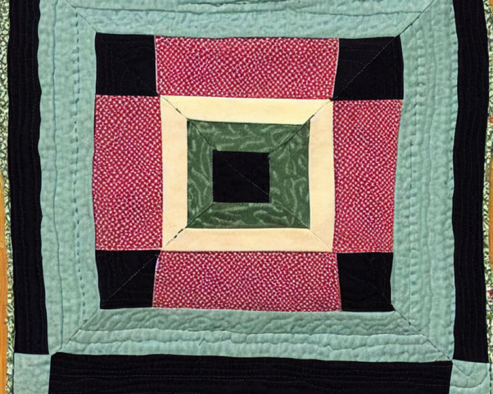 Geometric Quilt Pattern in Pink, Green, and Black on Quilted Fabric