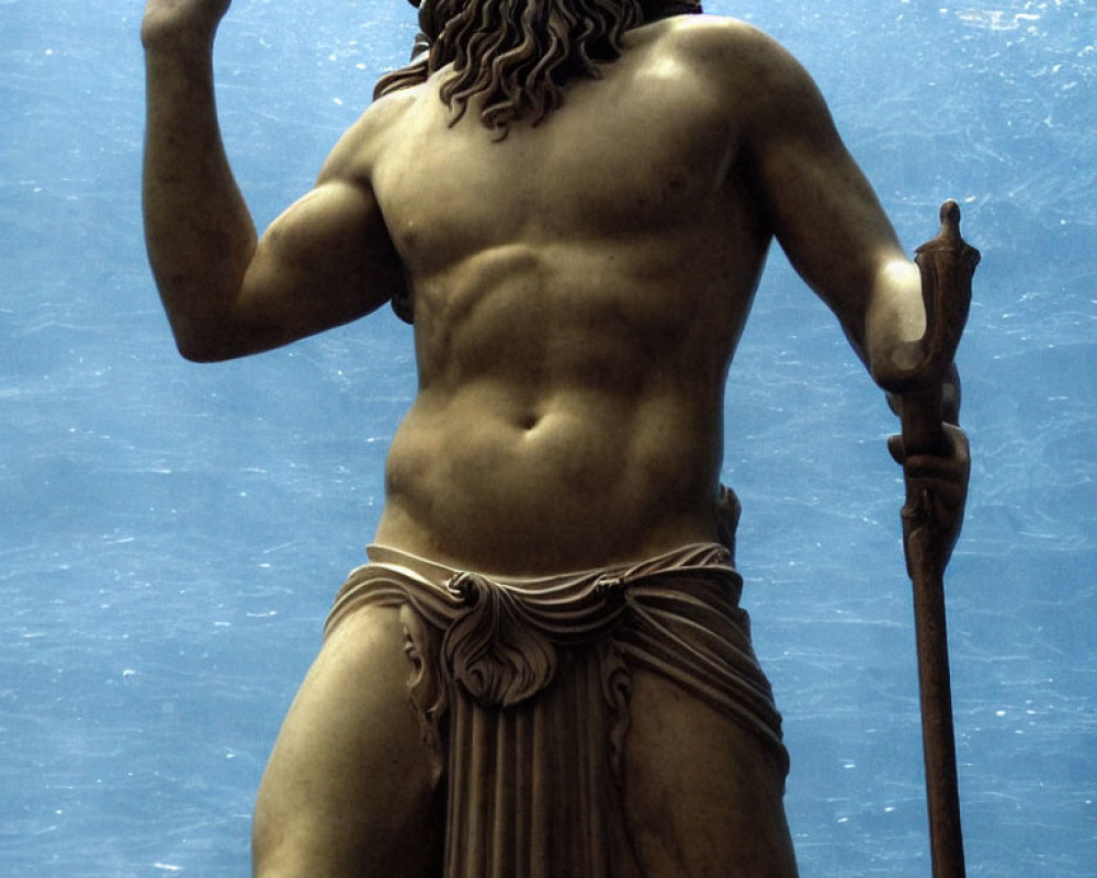 Muscular bearded male bronze statue with staff, gesturing against blue background