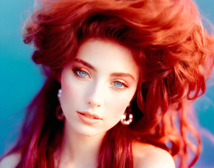 Vibrant red-haired woman with blue eyes on blue background