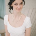 Ethereal woman in white feathered outfit with blue and gold headpiece gazes intently in