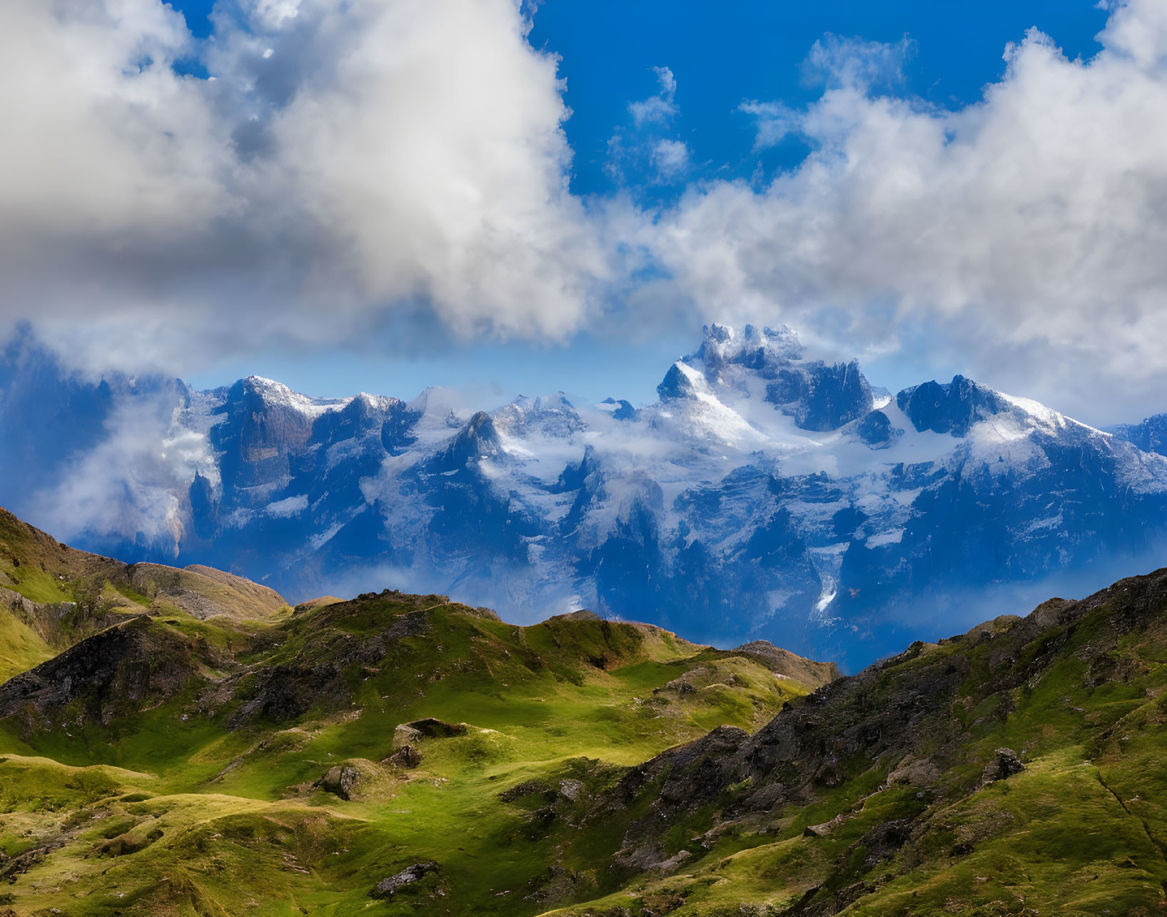 Green Hills and Snow-Capped Mountains under Cloudy Sky