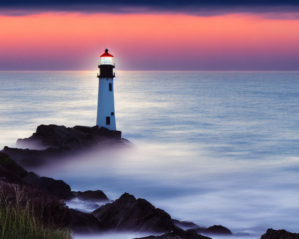 Tranquil seascape with white lighthouse, misty ocean, and colorful sunset sky