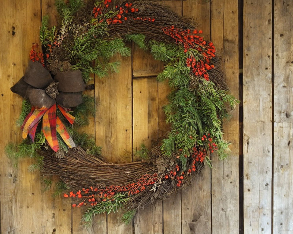 Festive wreath with red berries and green foliage on textured wooden wall