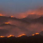 Mysterious orange glow illuminates mountain peaks through dense clouds