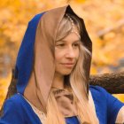 Portrait of woman with curly hair in blue cloak and green necklace on golden background with trees