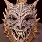 Ornate mask with horns, intricate carvings, and feathers depicting a fierce mythical or tribal