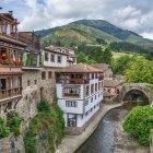 Scenic mountain village with stone bridges, balconied buildings, and church spire