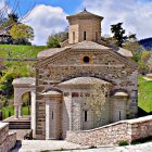 Multi-tiered stone building with golden domes in lush green setting