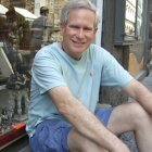 Elderly Man Smiling on Bench Against Rocky Background