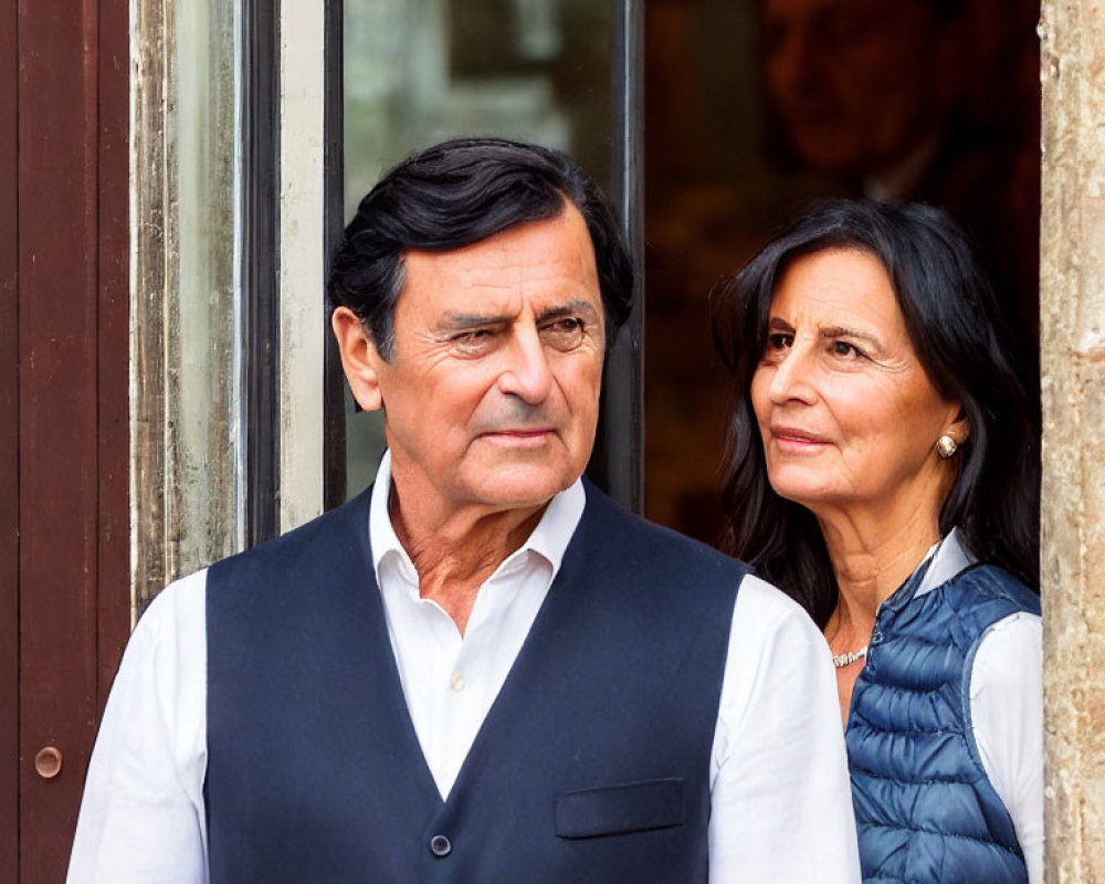 Man and woman in vests standing closely with reflective expressions.