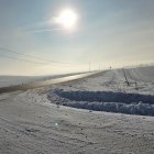 Snowy village with warm sun glow and church spire in winter landscape