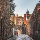 Quaint old town cobblestone street with snow and flowers