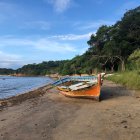 Tranquil beach scene with broken boat under vibrant blue sky