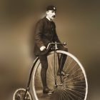 Vintage penny-farthing rider in bowler hat and suit with monocle