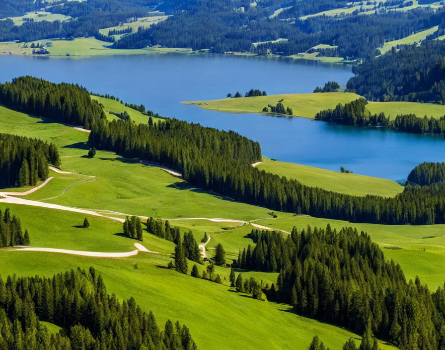 Scenic view of lush green hills, winding road, dense forests, and serene blue lake