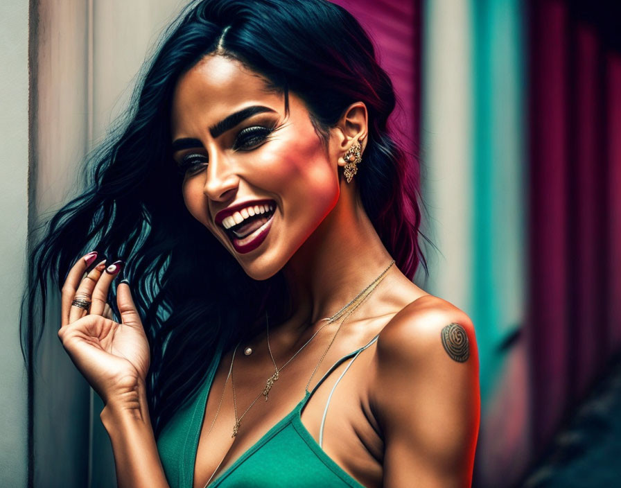 Smiling woman with dark hair in green top and jewelry on colorful backdrop