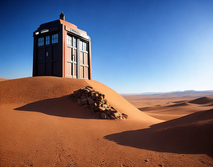 Blue police box on desert sand dune under clear blue sky