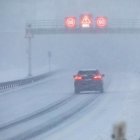 Snowy road with curvy tire tracks under hazy sky and diffused sun