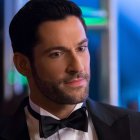 Man in tuxedo with beard and red boutonniere in dimly lit room