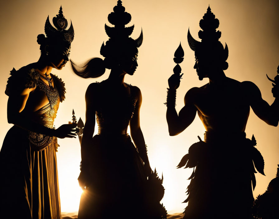 Silhouetted figures in ornate costumes and headdresses against warm backdrop