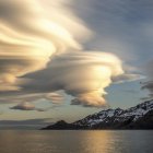 Unique Mushroom Structures in Surreal Landscape with Calm Lake and Parachute-Like Object