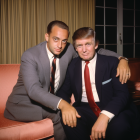 Two stern male characters in suits on a couch, one in a green beret