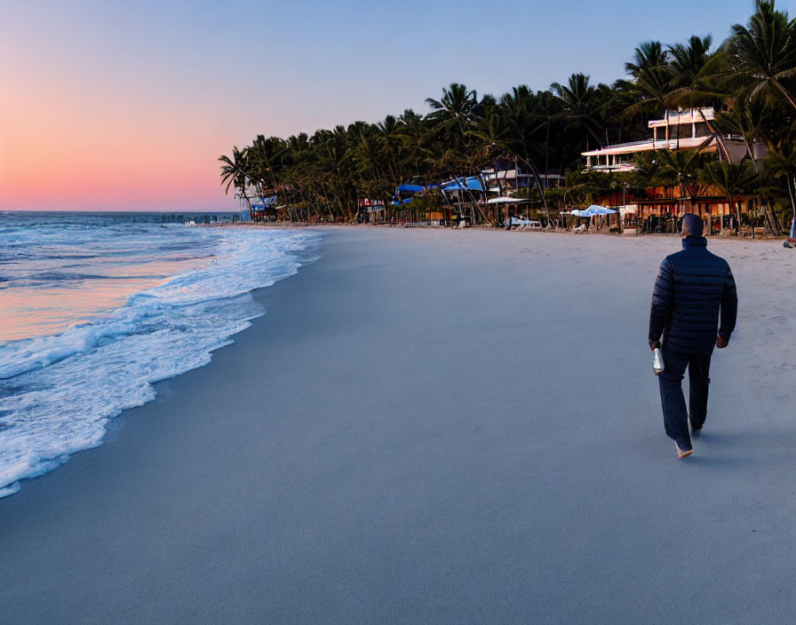 Solitary figure strolling on sandy beach at dusk